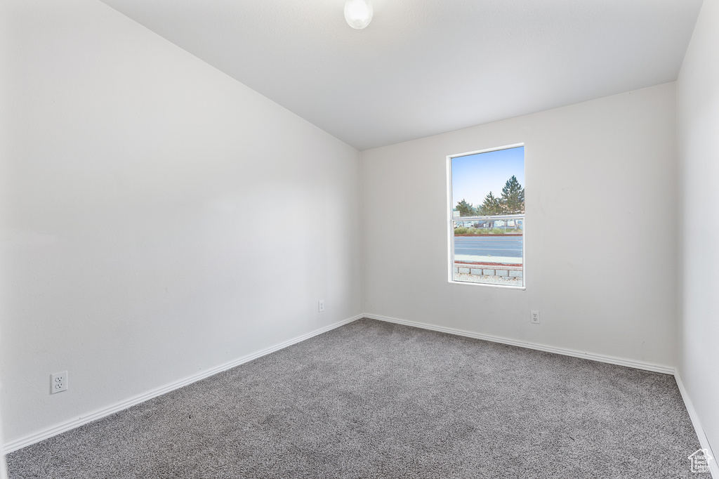 Unfurnished room featuring carpet and vaulted ceiling