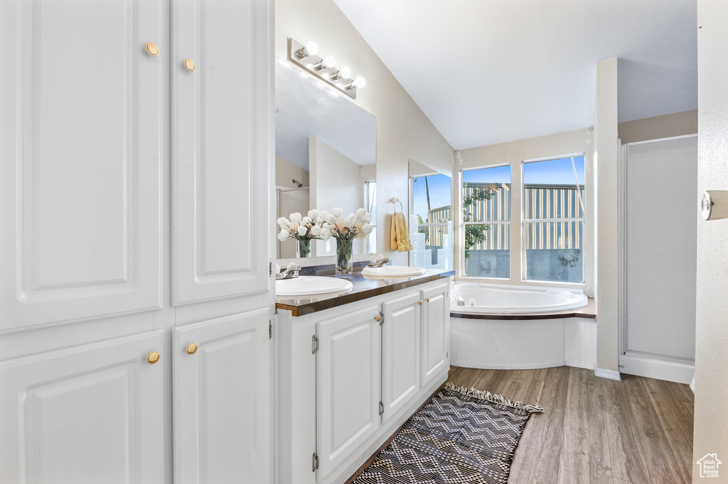 Bathroom featuring vaulted ceiling, hardwood / wood-style flooring, separate shower and tub, and vanity