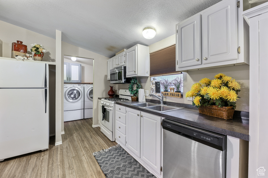 Kitchen featuring sink, stainless steel appliances, white cabinetry, and light hardwood / wood-style flooring