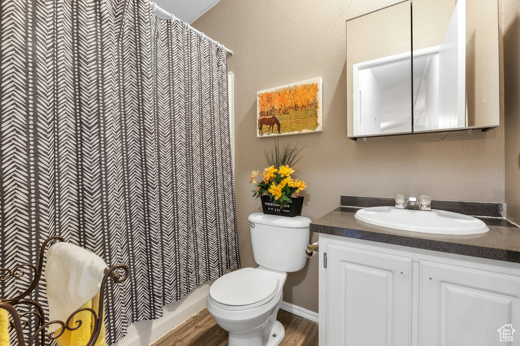 Full bathroom with hardwood / wood-style flooring, shower / bath combo, toilet, and vanity