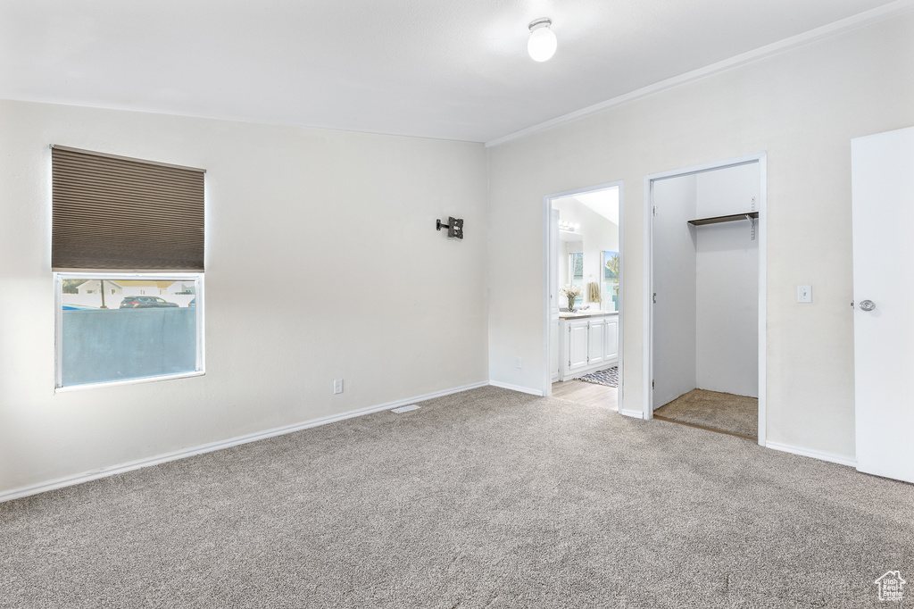 Unfurnished bedroom with a closet, light colored carpet, and ensuite bath