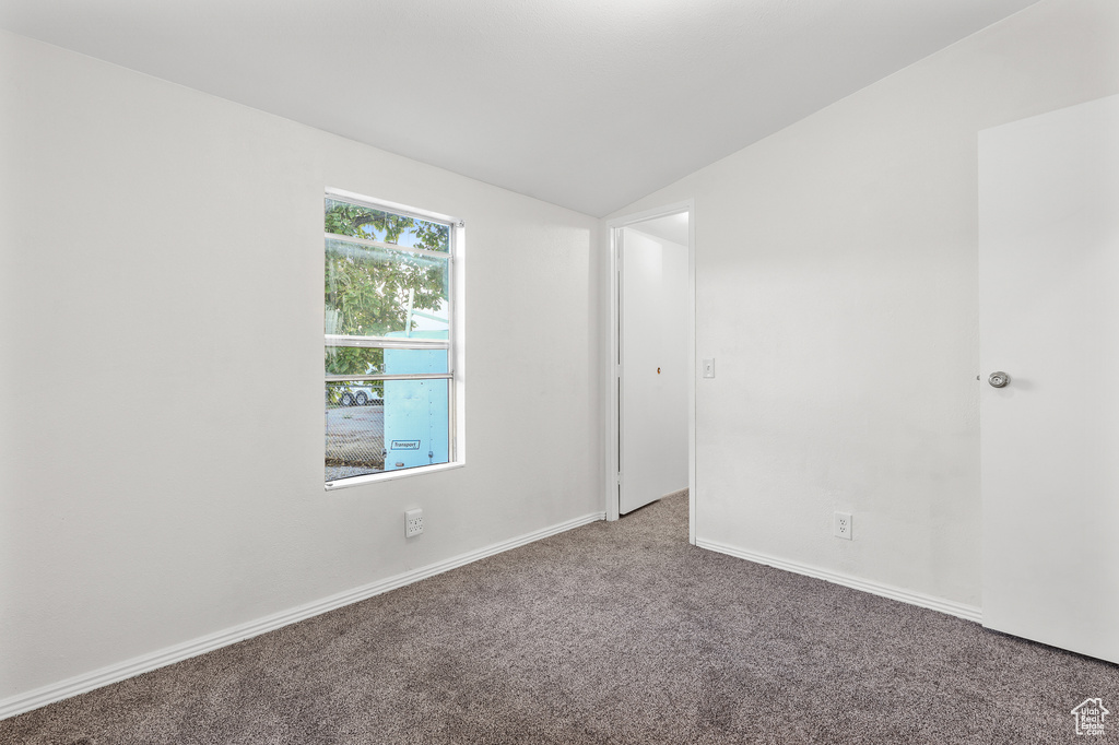 Spare room featuring carpet floors and lofted ceiling