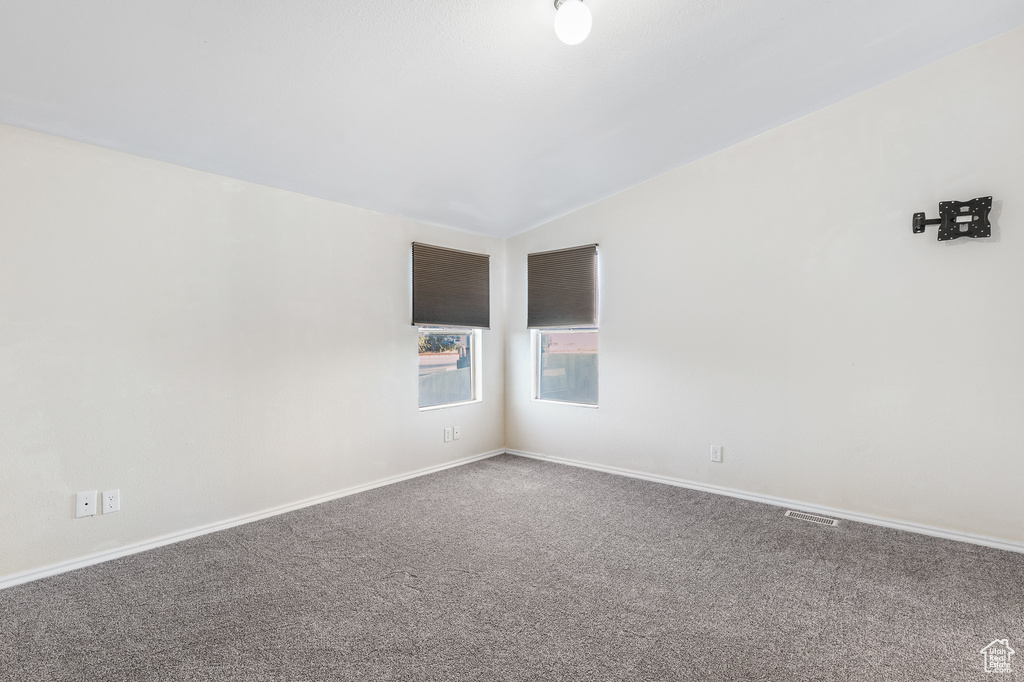 Carpeted empty room featuring lofted ceiling