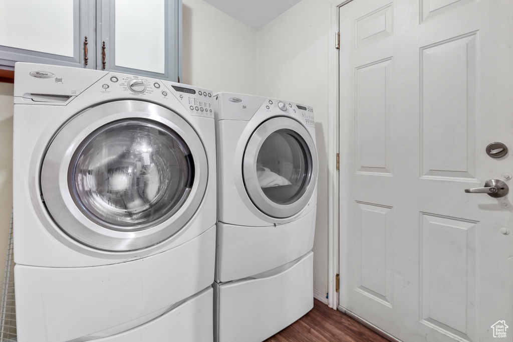 Laundry area featuring dark hardwood / wood-style flooring, cabinets, and washer and clothes dryer