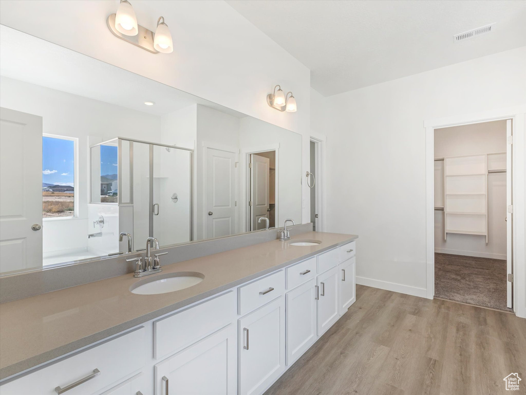 Bathroom with hardwood / wood-style floors, vanity, and a shower with shower door