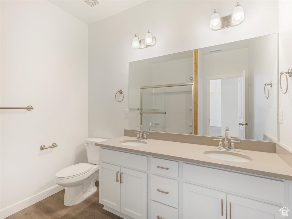 Bathroom featuring an enclosed shower, toilet, hardwood / wood-style flooring, and vanity