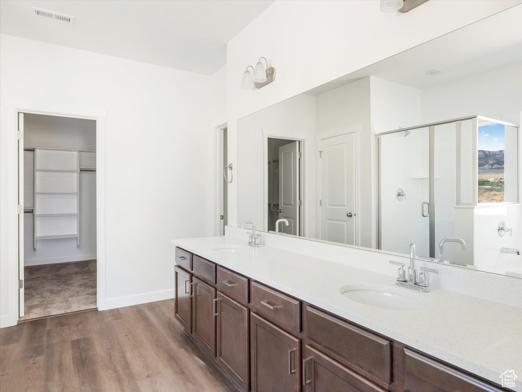 Bathroom with hardwood / wood-style floors, vanity, and a shower with shower door