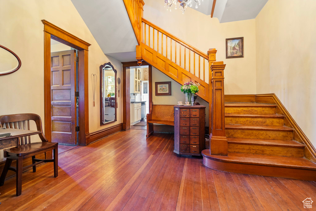 Stairs with high vaulted ceiling and hardwood / wood-style floors