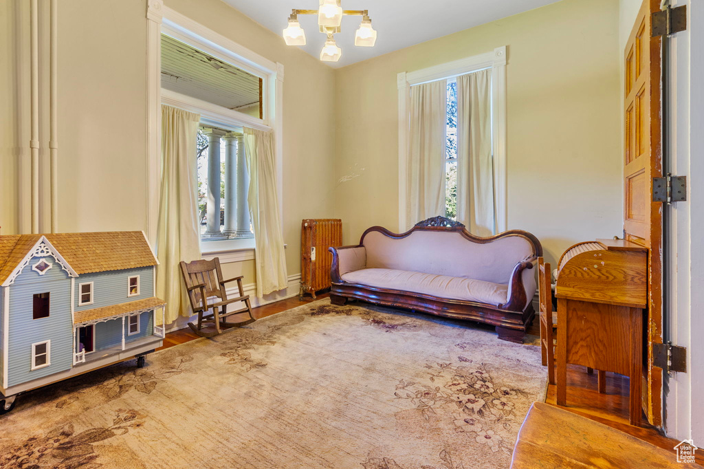 Sitting room featuring hardwood / wood-style flooring, a notable chandelier, radiator heating unit, and a healthy amount of sunlight