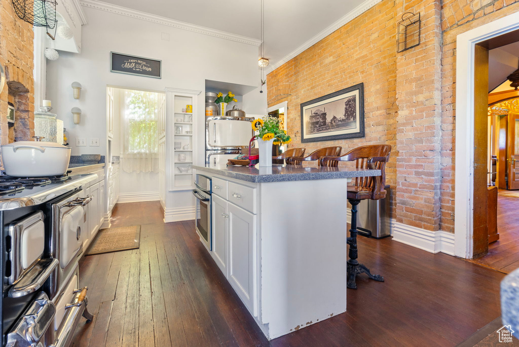 Kitchen with white cabinets, a breakfast bar, dark hardwood / wood-style floors, and oven