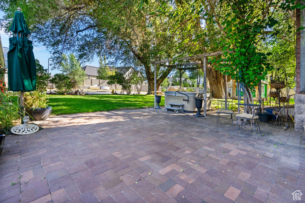 View of patio with a hot tub and a pergola