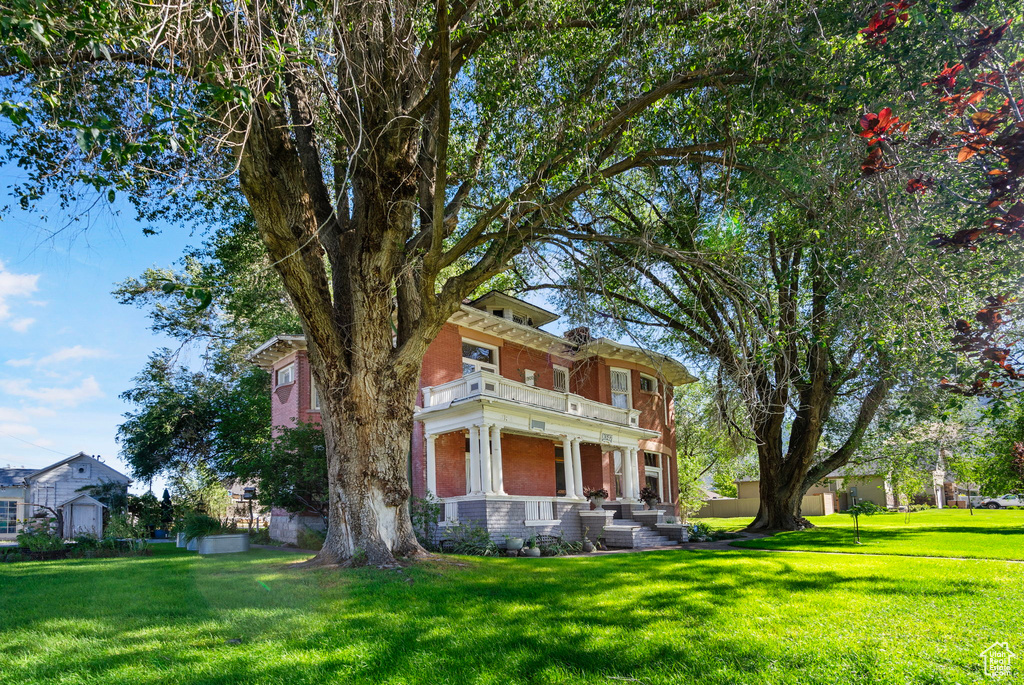 View of front facade featuring a balcony and a front yard