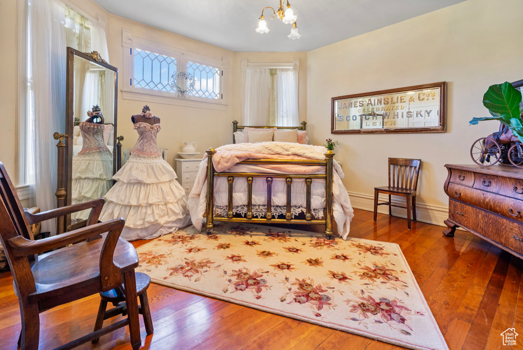 Bedroom featuring a baseboard radiator, wood-type flooring, and an inviting chandelier