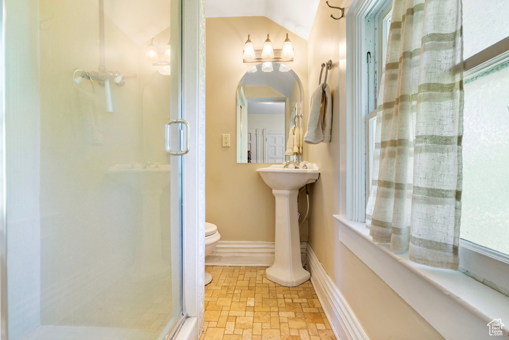 Bathroom featuring vaulted ceiling, a shower with door, and toilet