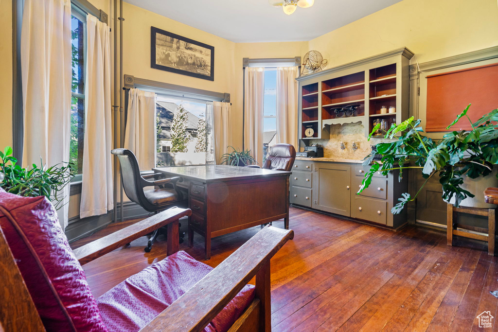 Office with dark wood-type flooring and a healthy amount of sunlight