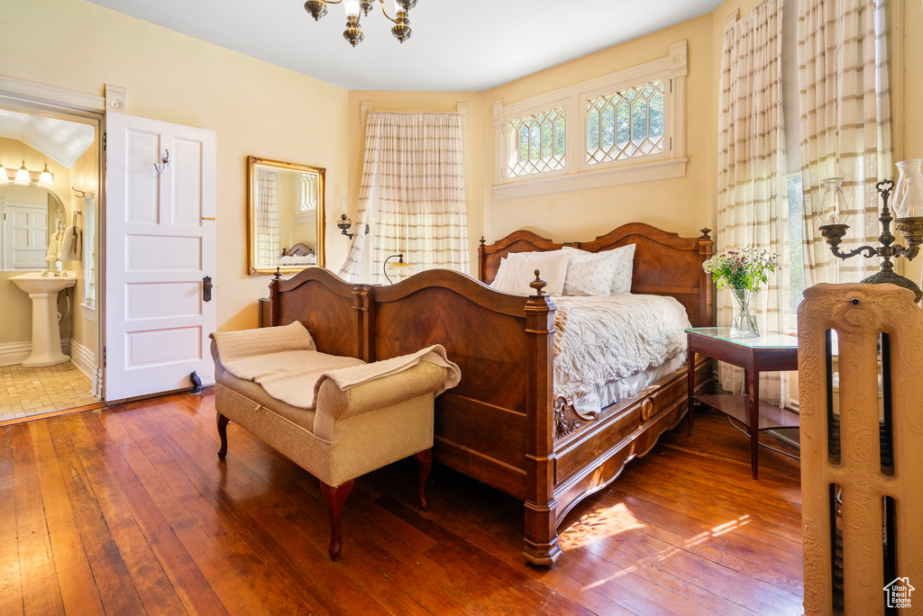 Bedroom with hardwood / wood-style flooring, connected bathroom, and a chandelier