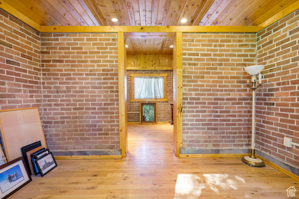 Interior space featuring hardwood / wood-style flooring, wooden ceiling, and brick wall