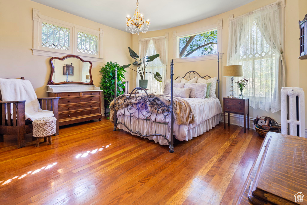 Bedroom featuring hardwood / wood-style floors, a chandelier, and radiator