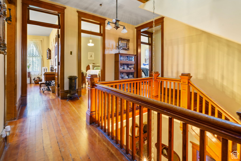 Corridor with vaulted ceiling, an inviting chandelier, and wood-type flooring