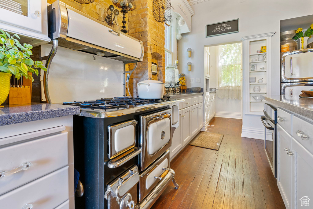 Kitchen featuring dark hardwood / wood-style floors, stainless steel oven, range hood, and white cabinets