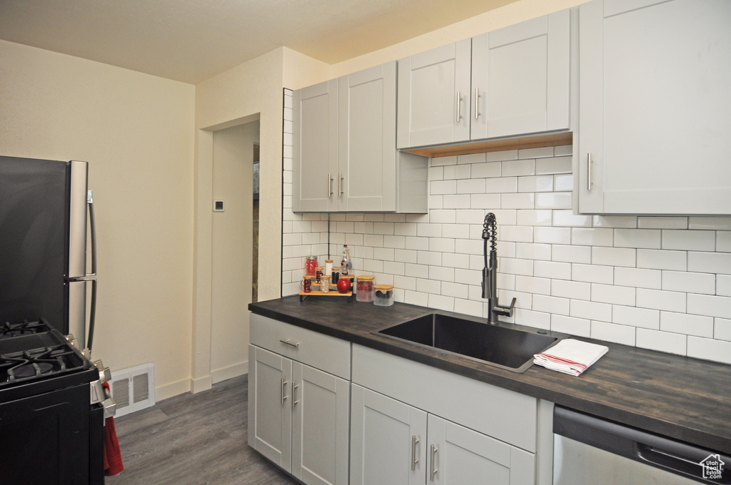 Kitchen with dishwasher, decorative backsplash, sink, fridge, and dark hardwood / wood-style flooring