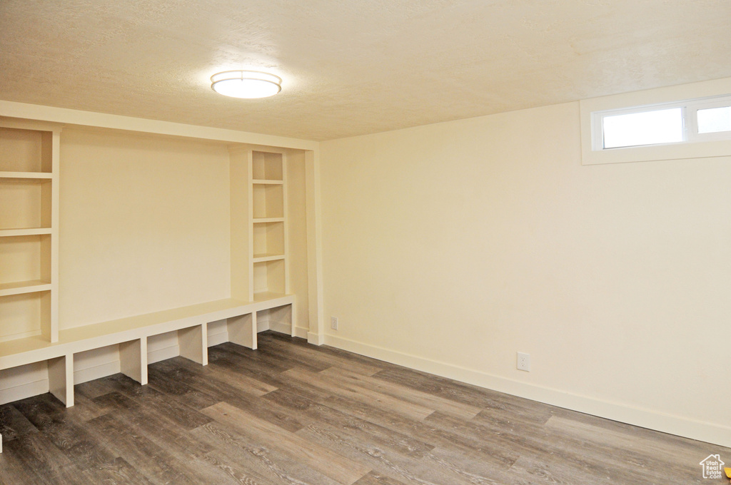 Basement with built in shelves, a textured ceiling, and hardwood / wood-style floors