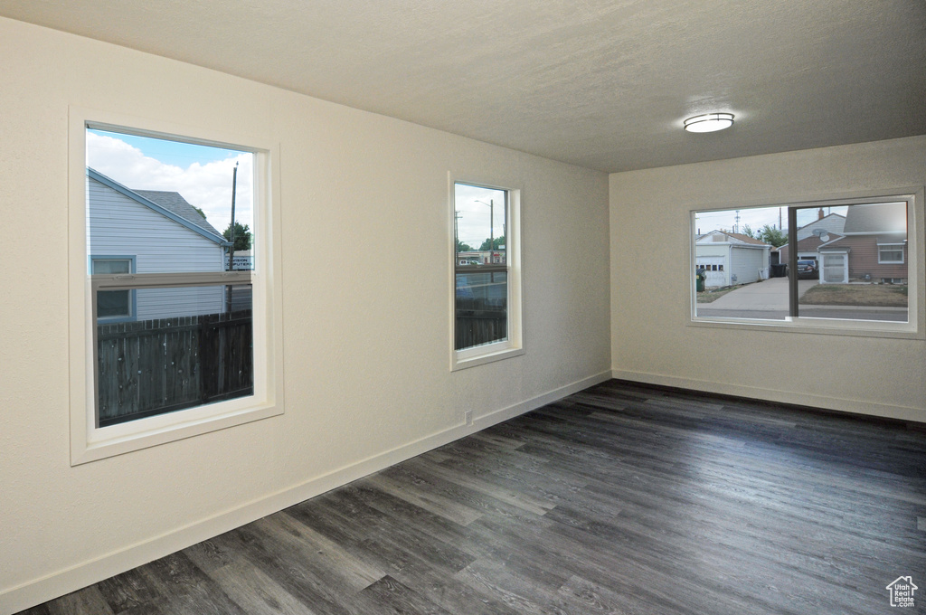 Empty room with dark hardwood / wood-style floors and a healthy amount of sunlight