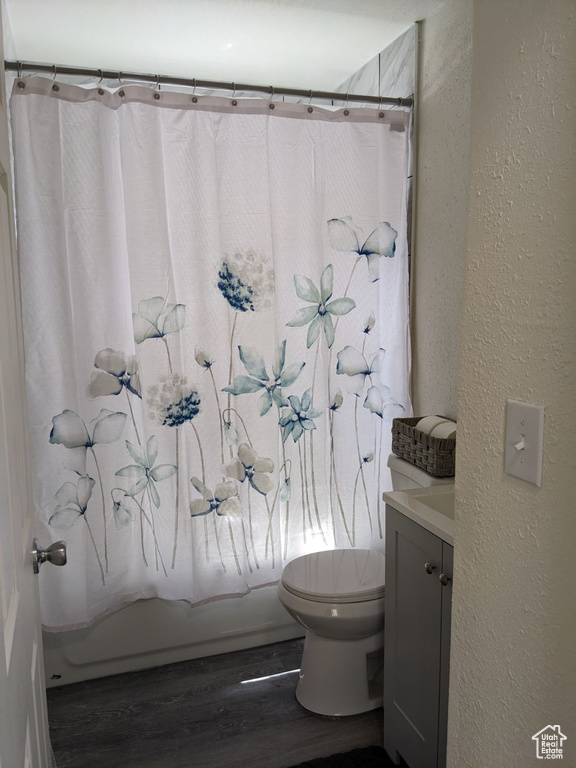 Full bathroom with vanity, toilet, hardwood / wood-style flooring, and shower / bath combo