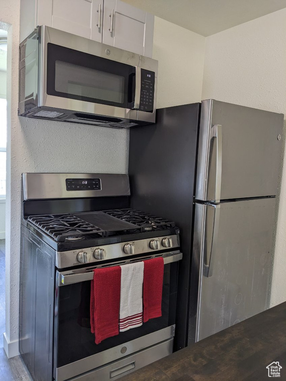 Kitchen featuring white cabinets, wood-type flooring, and stainless steel appliances