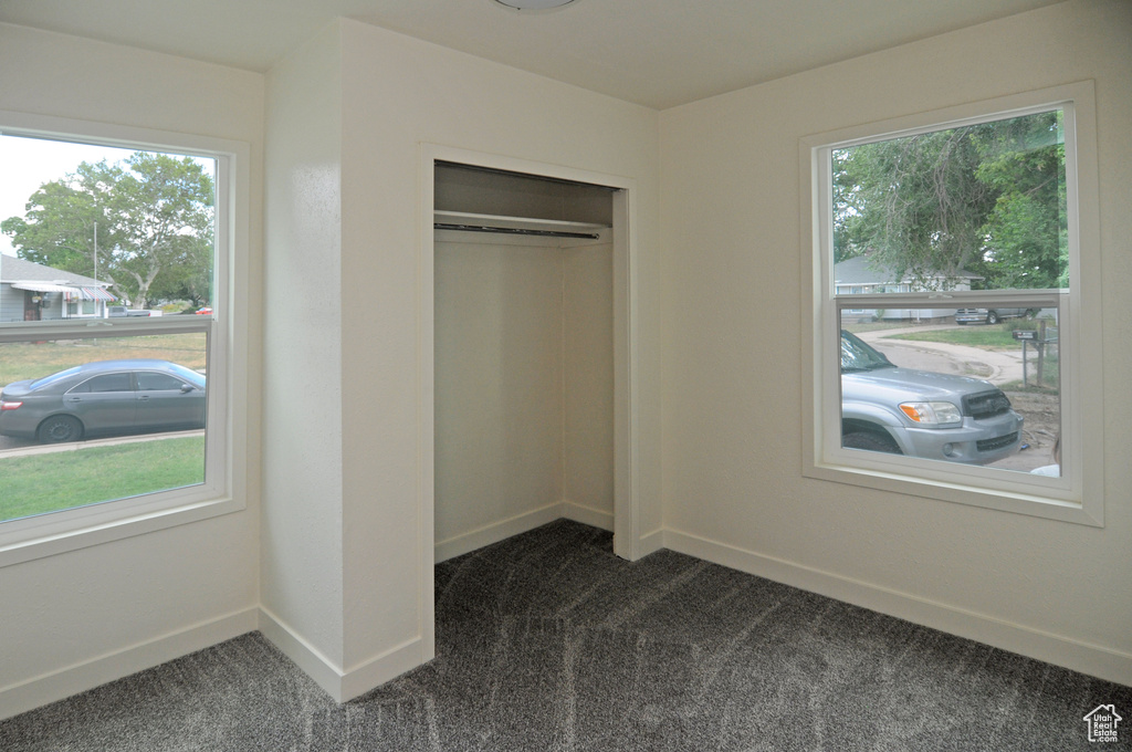 Unfurnished bedroom with a closet and dark carpet