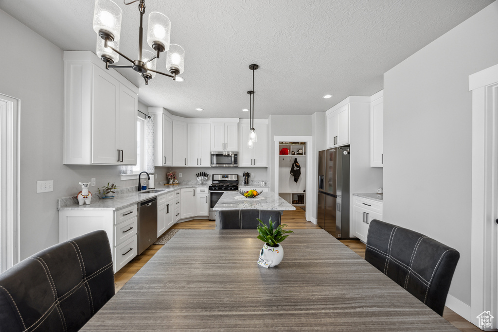 Dining area with sink, a chandelier, a textured ceiling, and wood-type flooring