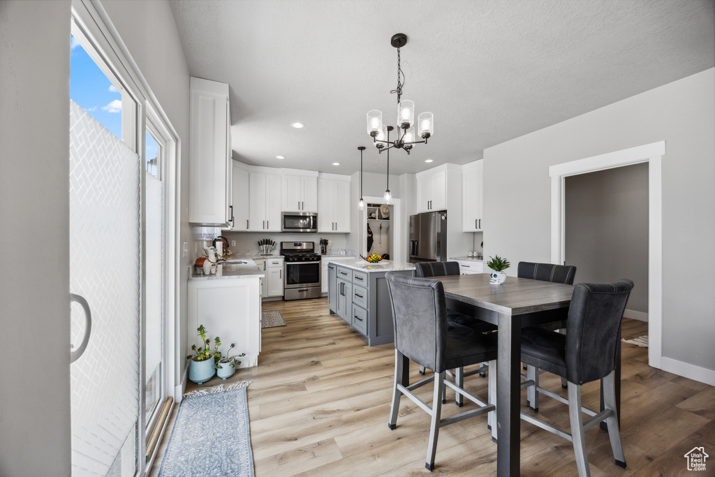 Dining space featuring sink, light hardwood / wood-style flooring, and a notable chandelier