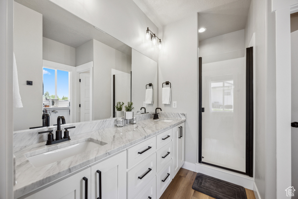 Bathroom featuring vanity, hardwood / wood-style floors, and a shower with shower door