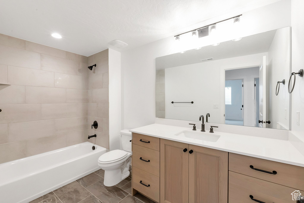 Full bathroom featuring tiled shower / bath combo, vanity, and toilet