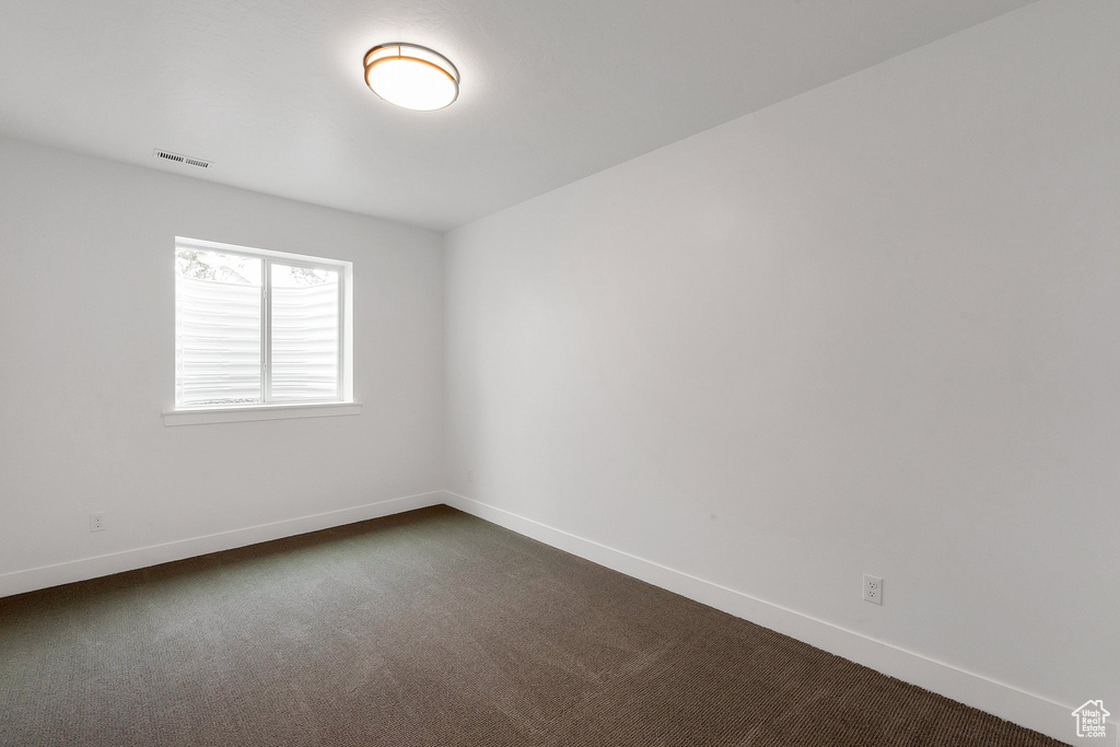 Empty room featuring dark colored carpet