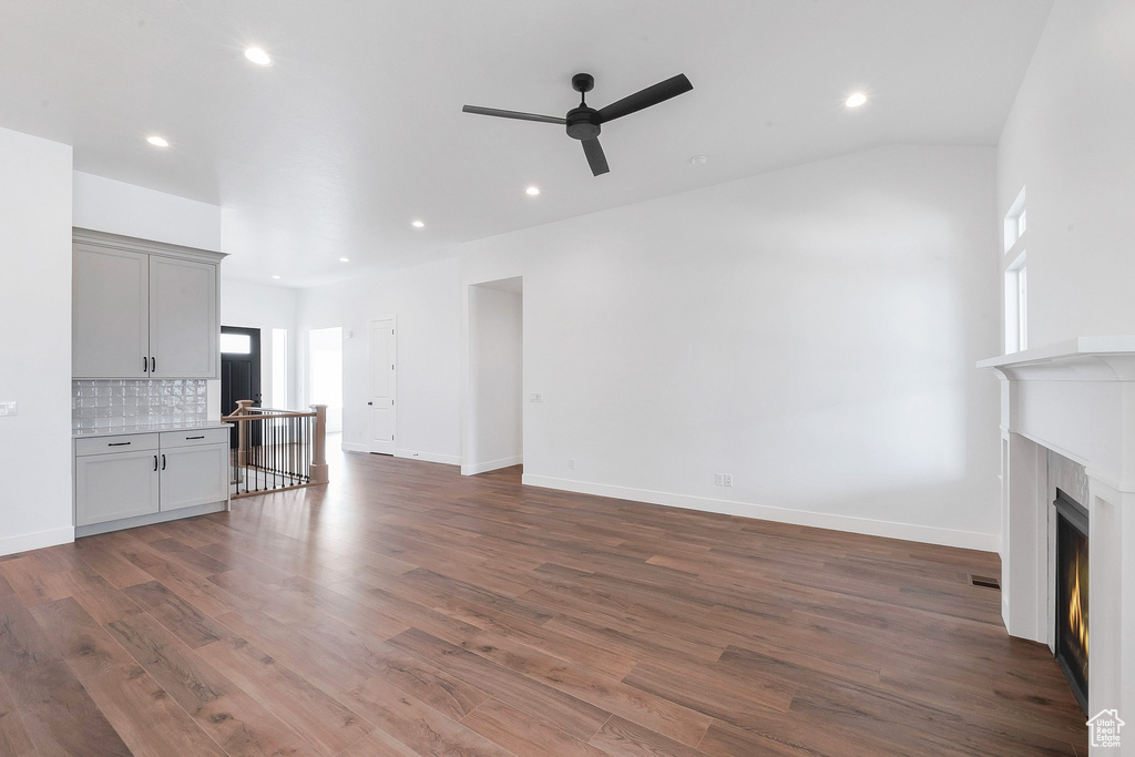 Unfurnished living room featuring vaulted ceiling, wood-type flooring, and ceiling fan