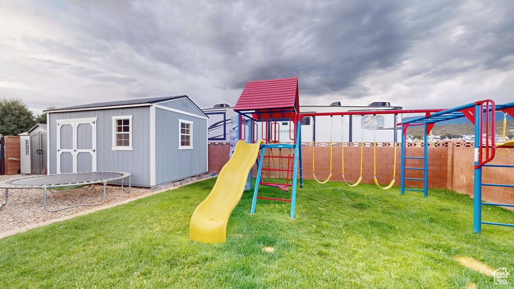 View of play area featuring a trampoline, a shed, and a lawn