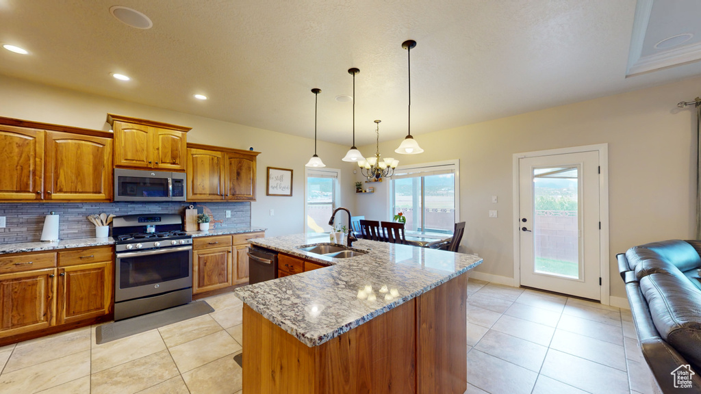 Kitchen with tasteful backsplash, appliances with stainless steel finishes, light stone countertops, light tile patterned floors, and sink