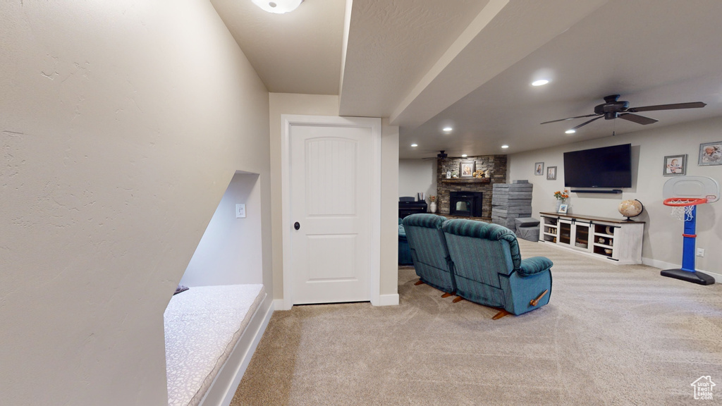 Carpeted living room with ceiling fan and a stone fireplace