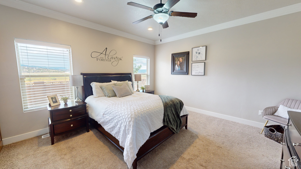 Bedroom with ceiling fan, light carpet, and crown molding