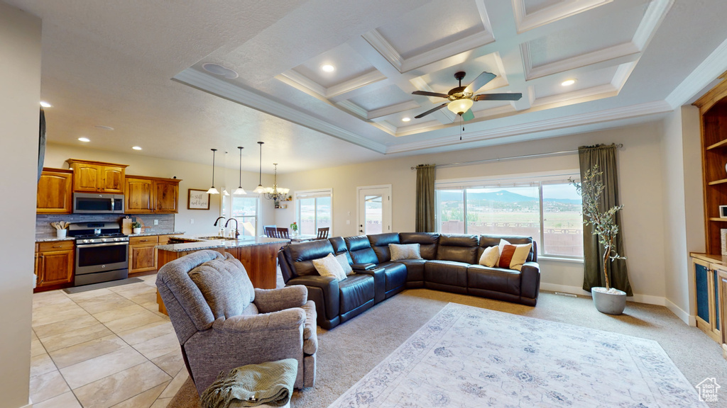 Living room with ornamental molding, coffered ceiling, sink, ceiling fan with notable chandelier, and light tile patterned floors