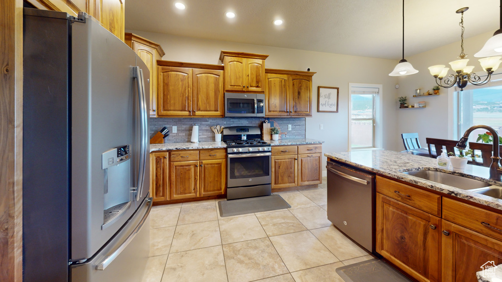 Kitchen featuring pendant lighting, a chandelier, tasteful backsplash, appliances with stainless steel finishes, and light tile patterned floors