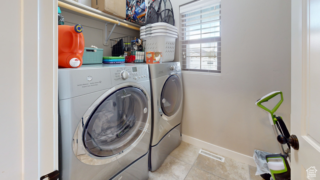 Washroom with light tile patterned floors and washing machine and dryer