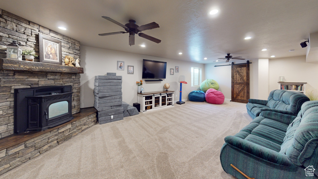 Living room with carpet flooring, ceiling fan, and a wood stove