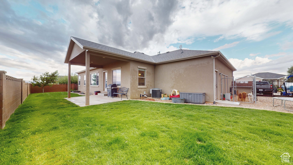 Rear view of property with a patio, a yard, and central air condition unit