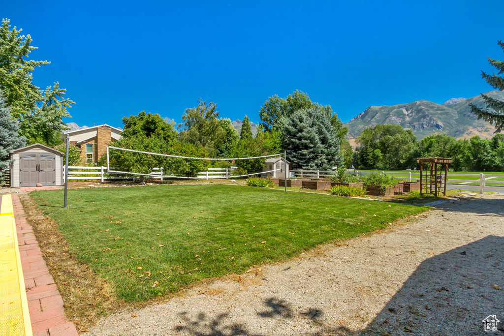 Exterior space featuring a lawn, a mountain view, a storage unit, and volleyball court