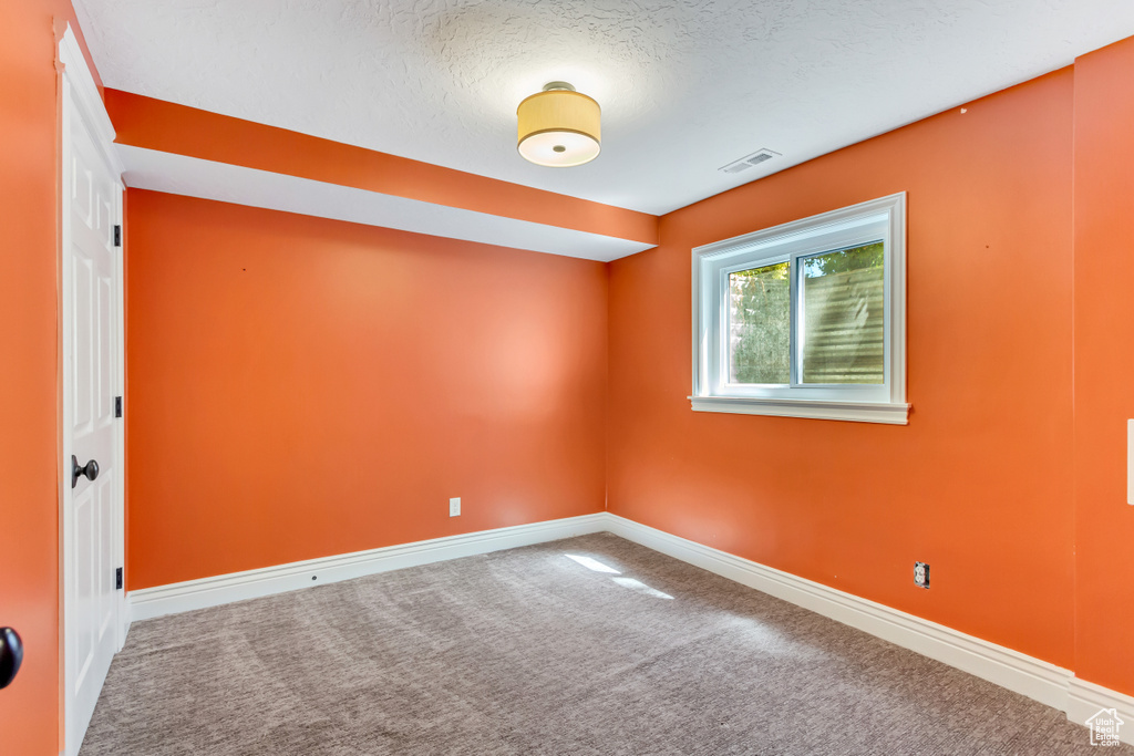 Unfurnished room with a textured ceiling and carpet floors