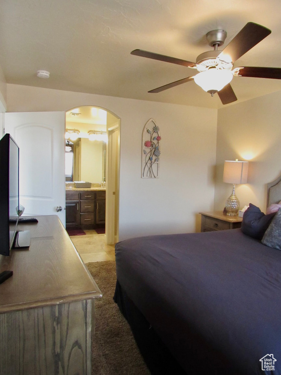 Bedroom featuring ceiling fan, connected bathroom, and light colored carpet