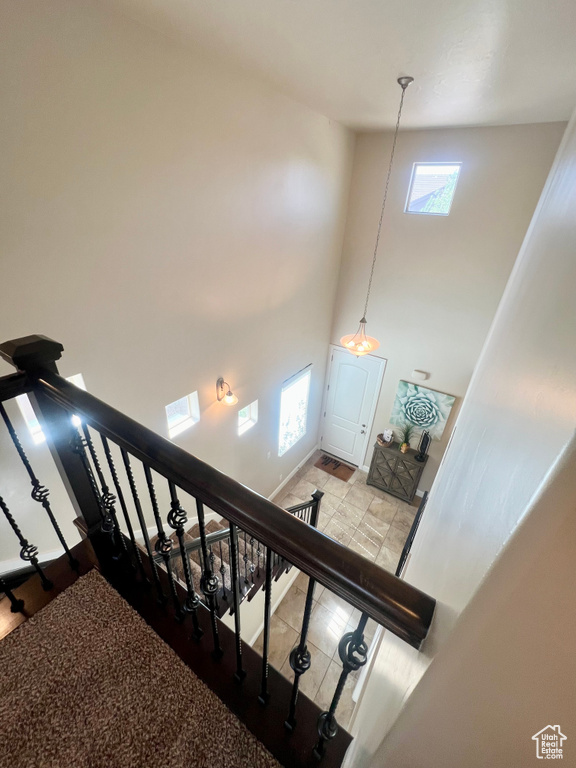 Staircase featuring high vaulted ceiling and tile patterned floors