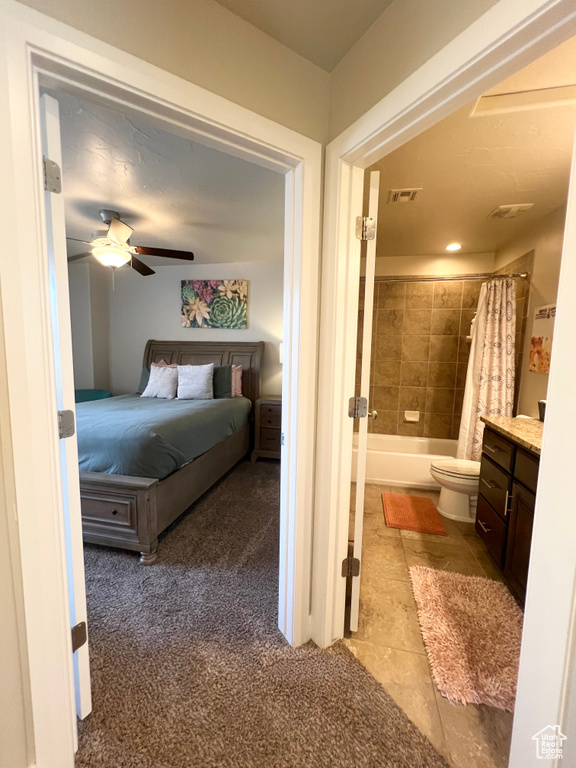 Bedroom featuring light colored carpet, ensuite bathroom, and ceiling fan